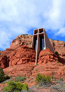 Chapel of the Holy Cross built high into the red rocks of Sedona, Arizona with blue sky in the background.