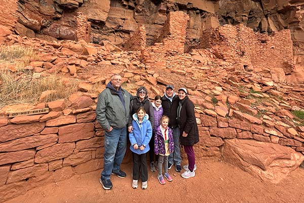 Multigenerational family posing in front of the cliff dwellings at the Honanki Heritage Site during Pink Jeep Tours’ Ancient Ruin Tour in Sedona, Arizona.