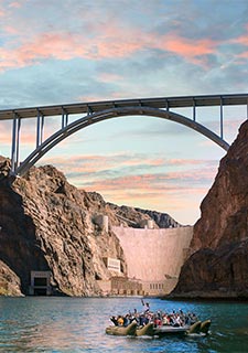 Sunset view of pontoon boat floating on the Colorado River in the Black Canyon, below Hoover Dam and the Mike O'Callaghan-Pat Tillman Memorial Bridge.