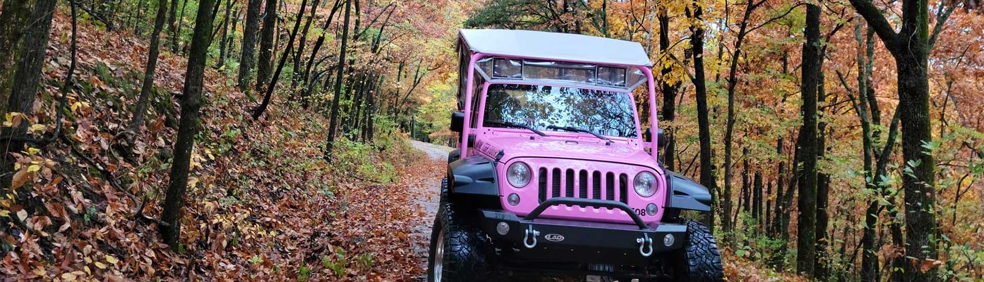 Front view of a Pink Jeep Wrangler surrounded by autumn trees on the Baird Mountain offroad trail, Pink Jeep Tours Branson.
