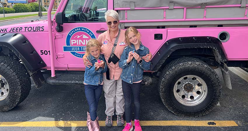 Grandma and two cute young girls smiling while posing beside a Pink Jeep Wrangler, Best of Branson Tour, Pink Jeep Tours.