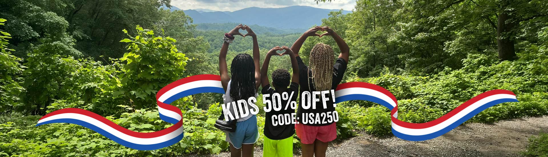 Three children stand looking out across the Smokies, forming hearts with their hands above their heads. A red, white and blue ribbon wraps behind them with the words "Kids 50% Off! Code: USA250"
