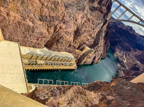 The Colorado River winds away from the massive Hoover Dam, passing beneath the Pat Tillman Memorial Bridge