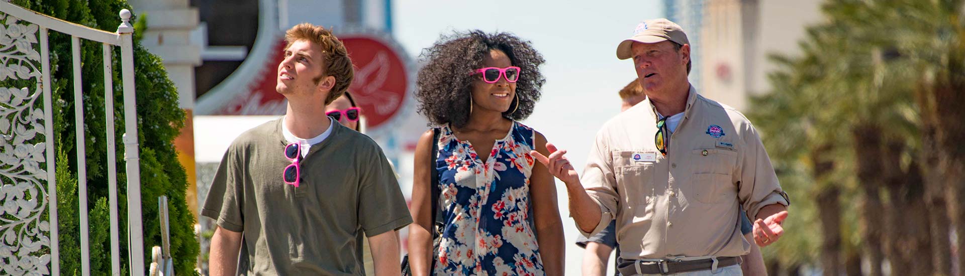 Pink Jeep Tours Las Vegas adventure guide and two guests walking towards the camera along Wedding Chapel Row.