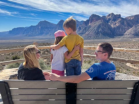 Family sitting on a park bench looking out towards the beautiful landscape of Red Rock Canyon near Las Vegas, Pink Jeep Tours.