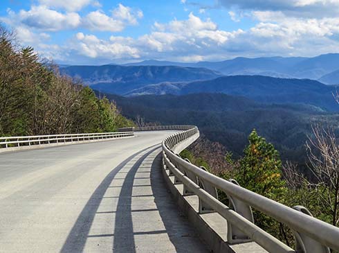 The Foothills Parkway curving through the Great Smoky Mountains National Park, with blue mountains in the distance during summer.