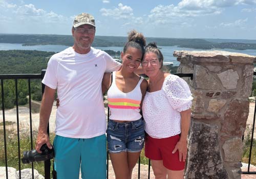 A couple and their daughter pose atop the summit of Baird Mountain, with Table Rock Lake stretching out behind them.