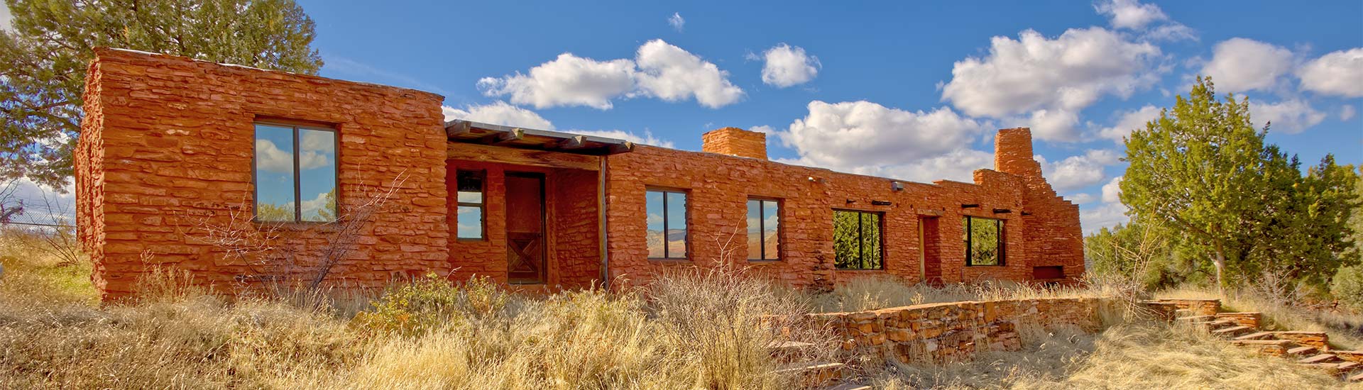 The historic Apache House at Red Rock State Park in Sedona, Arizona with bright blue sky and white clouds in the background.