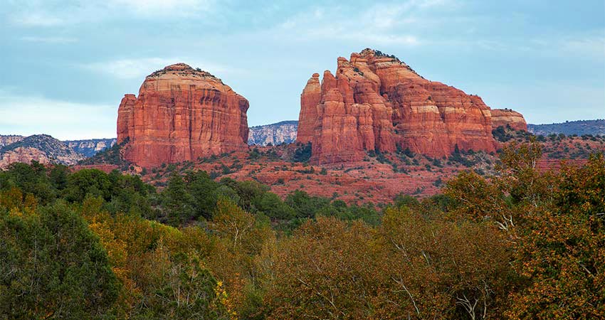 Close-up of crimson-colored Cathedral Rock and Courthouse Butte with treetops in the foreground, seen from Red Rock State Park in Sedona, AZ.