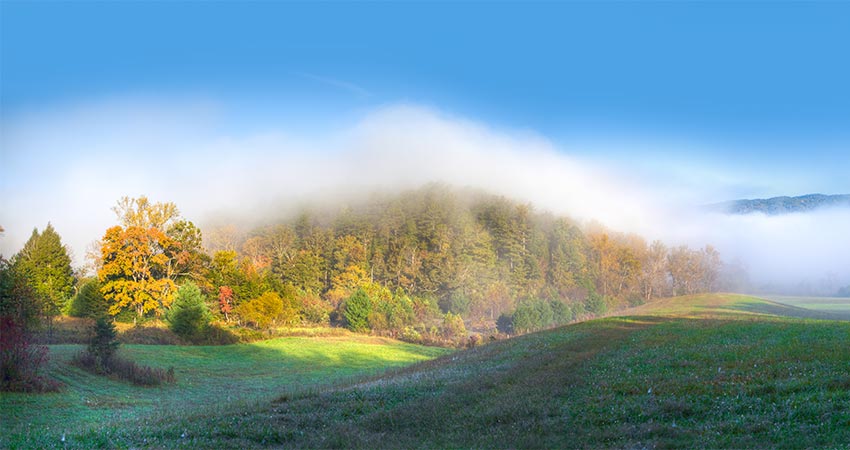 Morning mist falls over a scenic, rolling autumn landscape in Cades Cove Valley, Great Smoky Mountains National Park, TN.