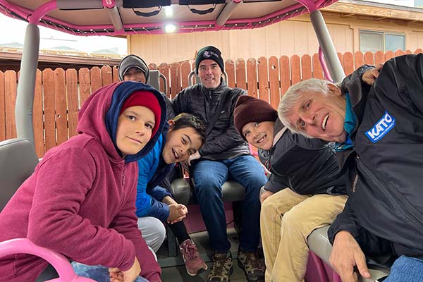Interior view of a Pink Jeep Wrangler with a father, four sons and a grandfather striking a fun pose while smiling at the camera, Pink Jeep Tours Sedona.