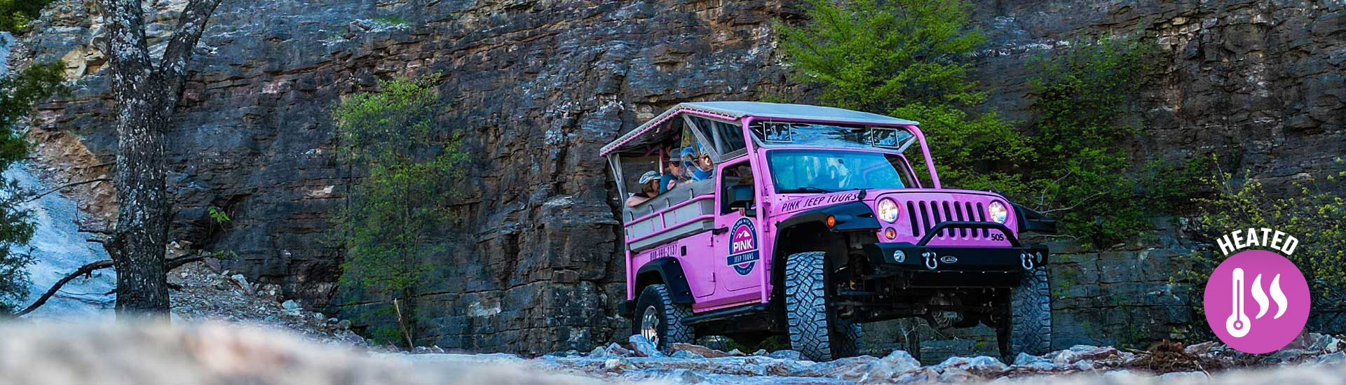 Pink Jeep Tours Branson Pink Jeep Wrangler driving through the rock quarry below Baird Mountain with heated jeep logo.