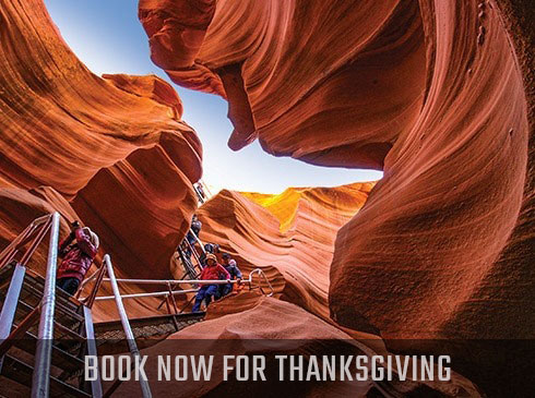 Visitors walking down staircase into Lower Antelope Canyon in Arizona, with book Now for Thanksgiving banner.