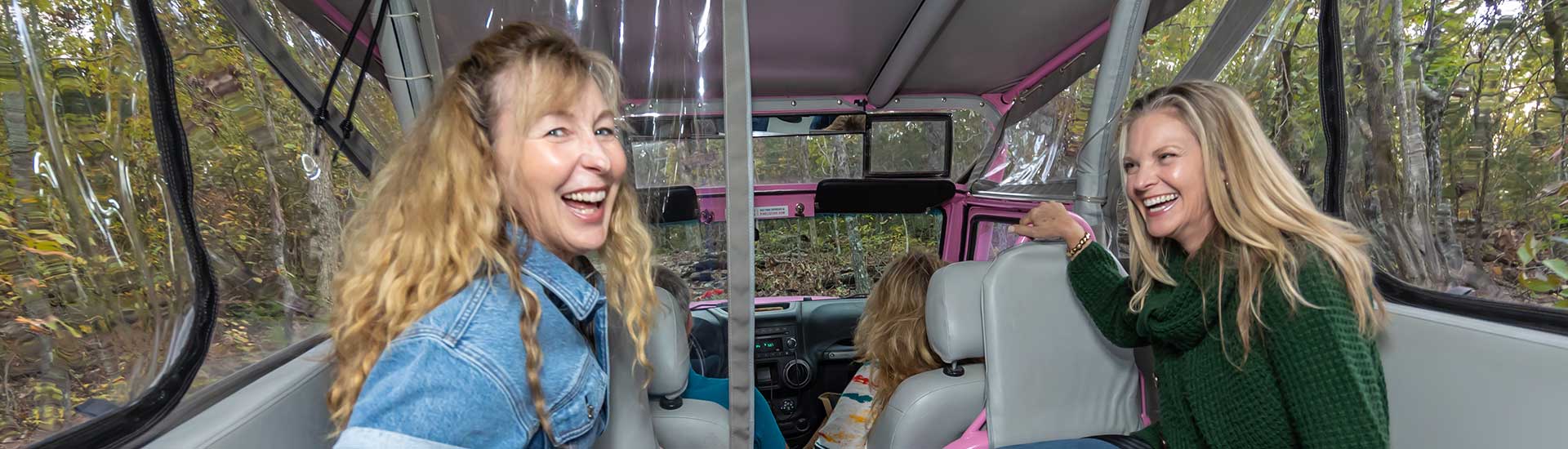 Closeup of two ladies laughing in the back of a Pink Jeep Wrangler while on the Baird Mountain off-road trail, Pink Jeep Tours Branson.