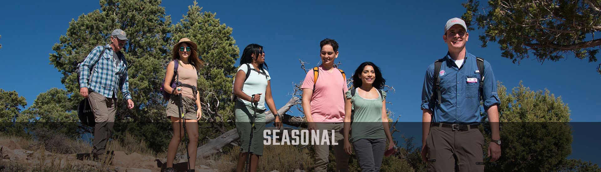 Pink® Jeep® Tours guide and guests hiking the Hermits Rest Trail, Grand Canyon with Seaonal banner.