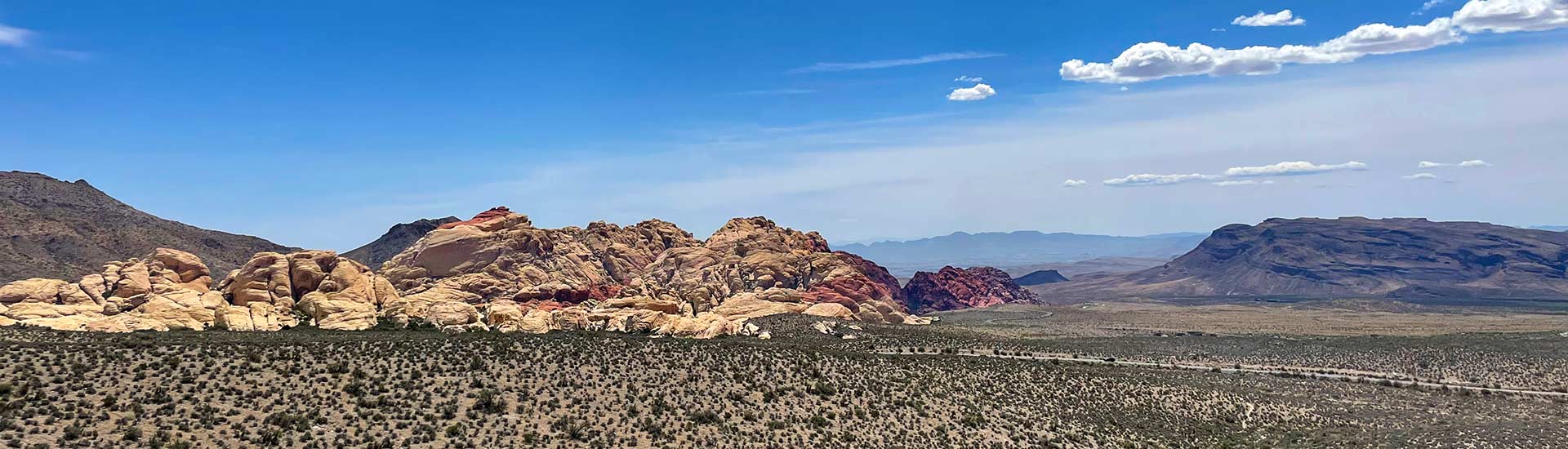 Beautiful panorama of the Red Rock Canyon National Conservation Area near Las Vegas, with blue sky and puffy clouds above, 